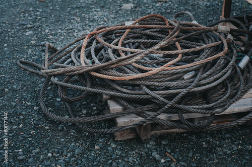 Foto Coiled heavy industrial steel wire rope with rusty texture on a wooden pallet outdoors