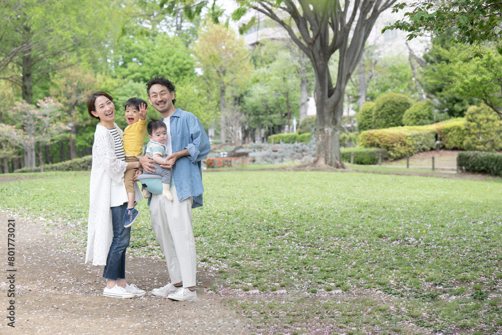 Fototapeta premium A friendly, smiling Japanese family playing in a backlit, freshly green park Wide-angle, camera-eye view