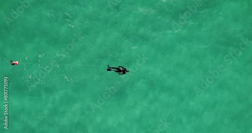 Solo spearfisher in vast turquoise sea, trailing a safety buoy during a clear day in Sardinia's waters. Italy aerial photo