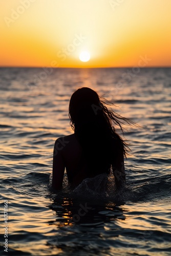 Back view of a womans silhouette against the shimmering ripples of the sea at sunset © miss[SIRI]