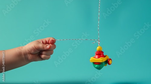 A child's hand pulling the string of a wind-up toy photo