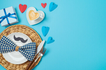 Table setting for Father's day breakfast with heart shape coffee cup, plate and gift box on blue background. Top view, flat lay