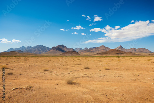 Expansive Desert Landscape with Distant Mountain Range Under Blue Sky