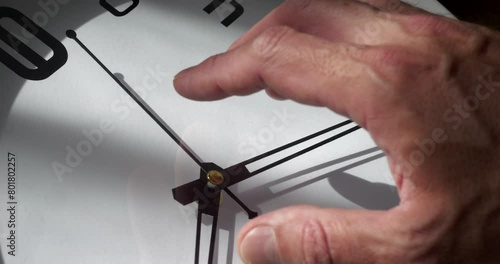 a man's hand over the dial of a large clock, the concept of the irrevocable flow of time photo