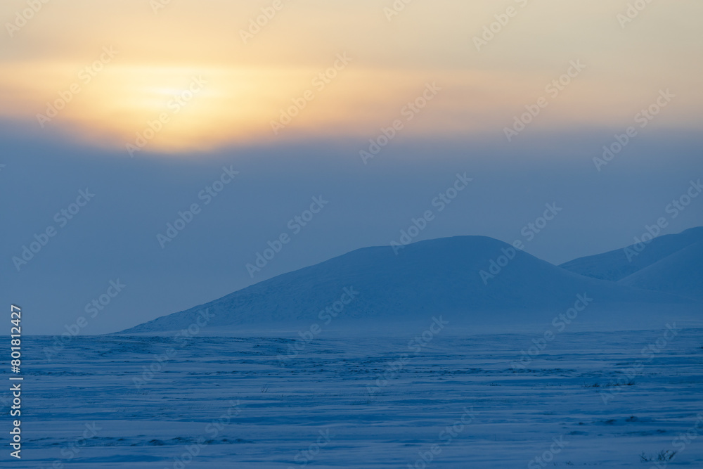 Winter arctic landscape. View of the snow-covered tundra and snow-capped mountains. Cold frosty winter weather. Endless Arctic Desert. Northern nature of the polar region. Sunset. Chukotka, Russia. Winter arctic landscape. View of the snow-covered tundra and snow-capped mountains. Cold frosty winter weather. Endless Arctic Desert. Northern nature of the polar region. Sunset. Chukotka, Russia.