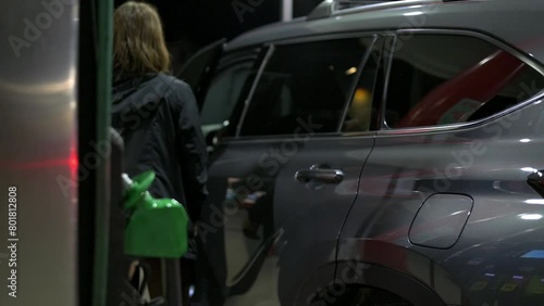 Eavening, woman finishes filling fuel at a gas station and gets into the car photo