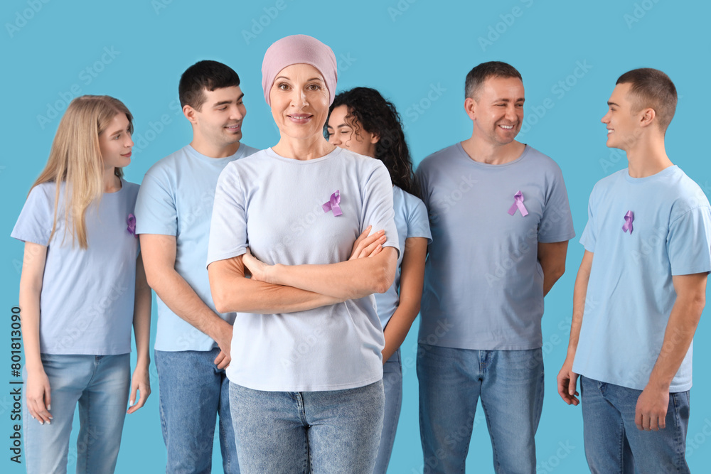 Mature woman after chemotherapy and people with lavender awareness ribbons on blue background. World Cancer Day