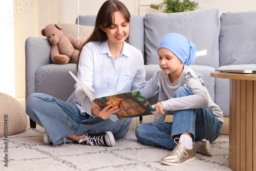 Little girl after chemotherapy with her mother reading story at home. International Childhood Cancer Day photo