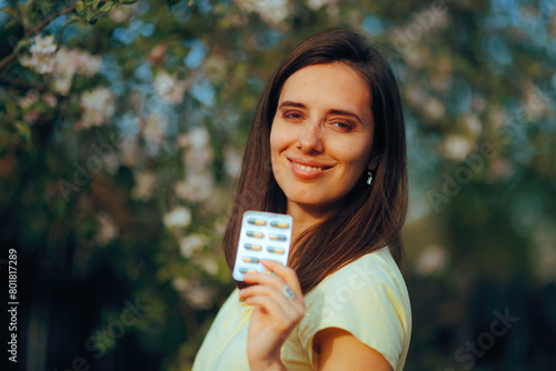 Smiling Woman Holding a Medicine Foil with Vitamin Supplements. Cheerful girl taking medication during spring asthenia season
