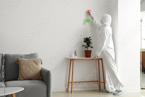 Female worker of cleaning service removing mold from wall in room photo