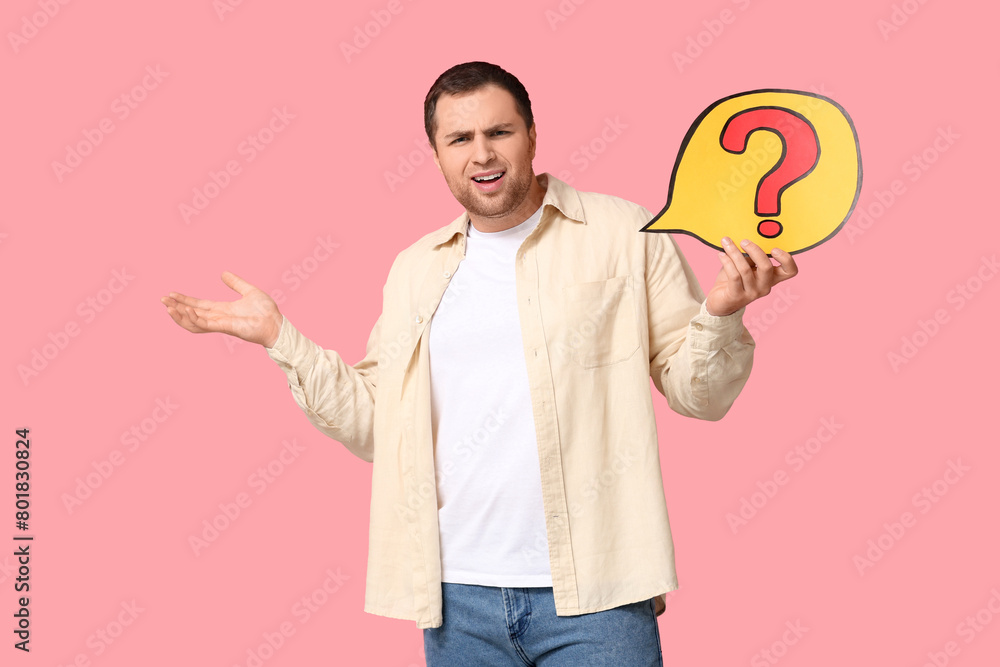 Confused young man with question mark on pink background Confused young man with question mark on pink background