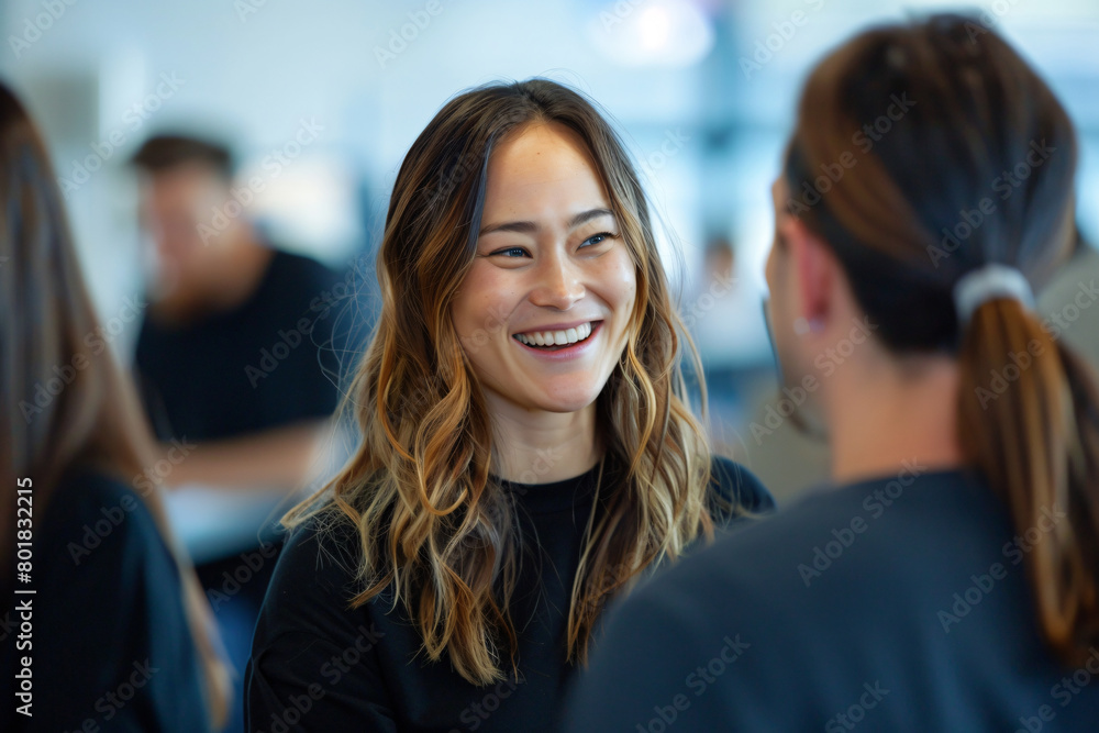 A photo of a business woman smiling and talking to two colleagues in an office setting with a blurred background showing other employees working A photo of a business woman smiling and talking to two colleagues in an office setting with a blurred background showing other employees working