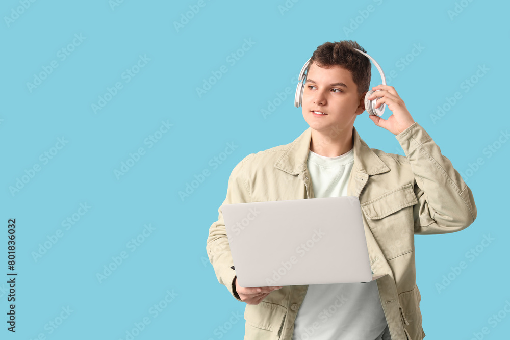 Teenage programmer in headphones with laptop on blue background Teenage programmer in headphones with laptop on blue background