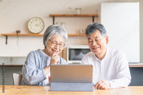 タブレットを使ってビデオ通話・テレビ電話する笑顔のシニア・高齢者夫婦  © buritora