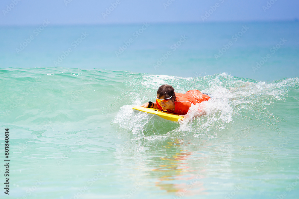 Child surfing on tropical beach. Surfer in ocean. Child surfing on tropical beach. Surfer in ocean.