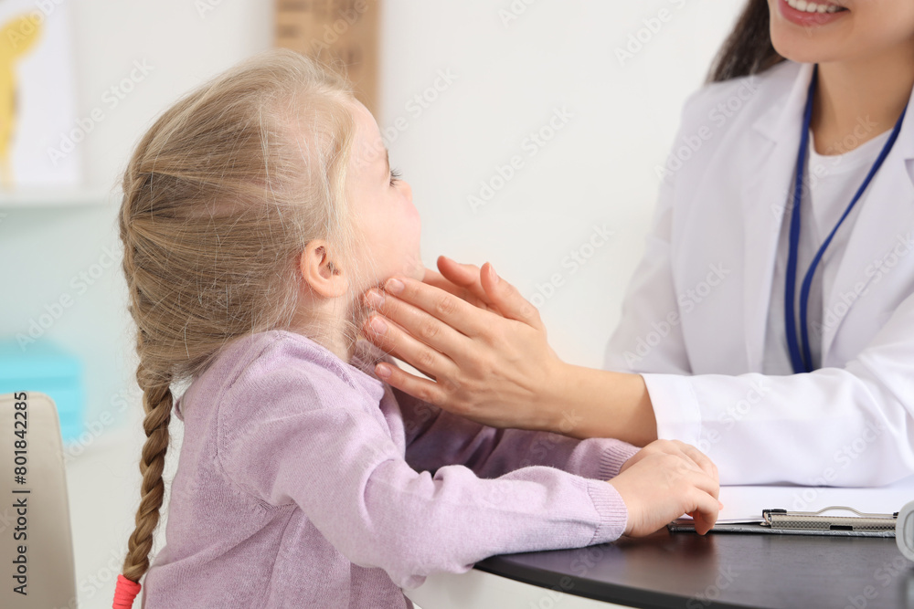 Female pediatrician examining little girl at table in clinic, closeup Female pediatrician examining little girl at table in clinic, closeup