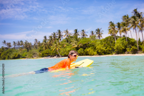 Child surfing on tropical beach. Surfer in ocean. © famveldman