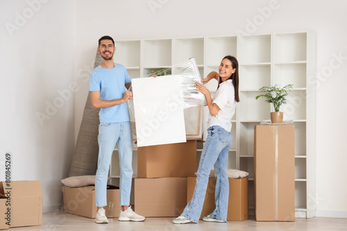 Young couple wrapping painting in room on moving day © Pixel-Shot