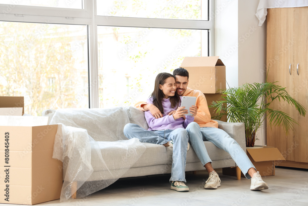 Young couple using tablet computer in room on moving day Young couple using tablet computer in room on moving day