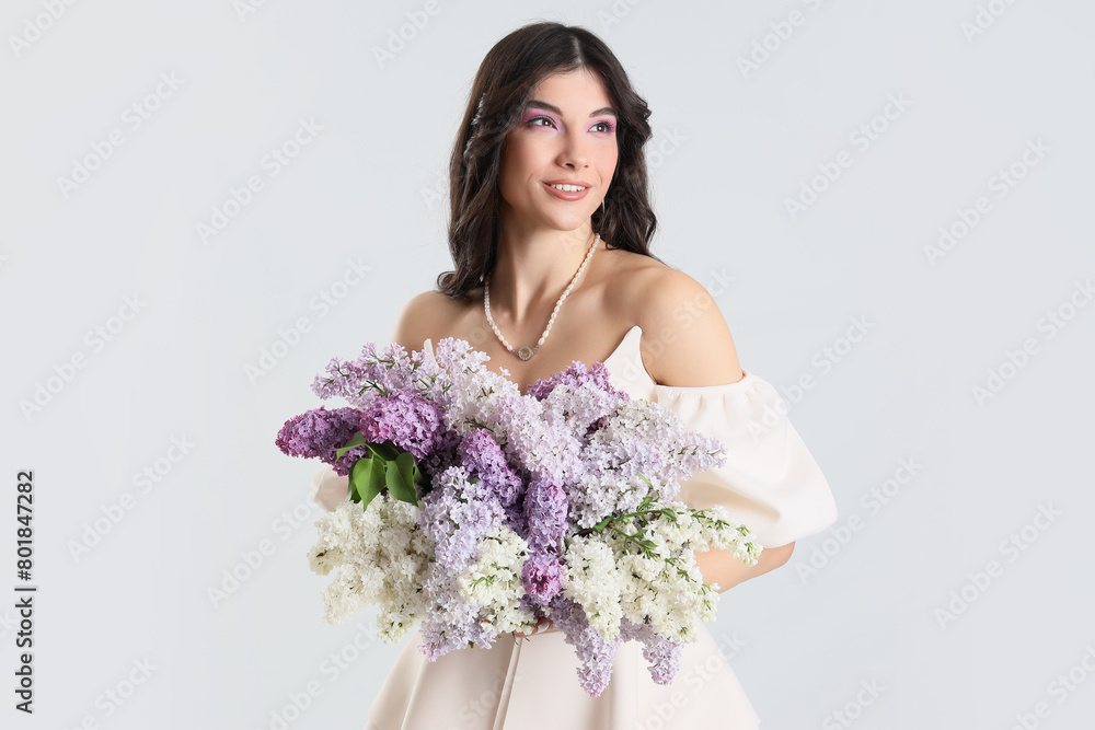 Beautiful young woman with lilac flowers on light background Beautiful young woman with lilac flowers on light background
