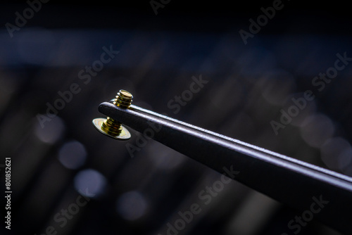 Stainless steel precision tweezers holding machine flat screw. Picking tool. photo