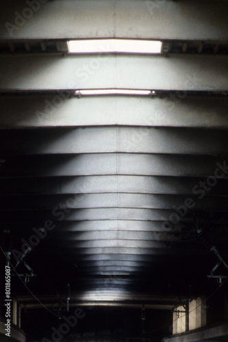 Vertical image of sky lights in roof space. natural sunlight white blurry pattern. black wall space. two small window embrasures with back lighting. Location Euston Railway Station London UK 2003 photo