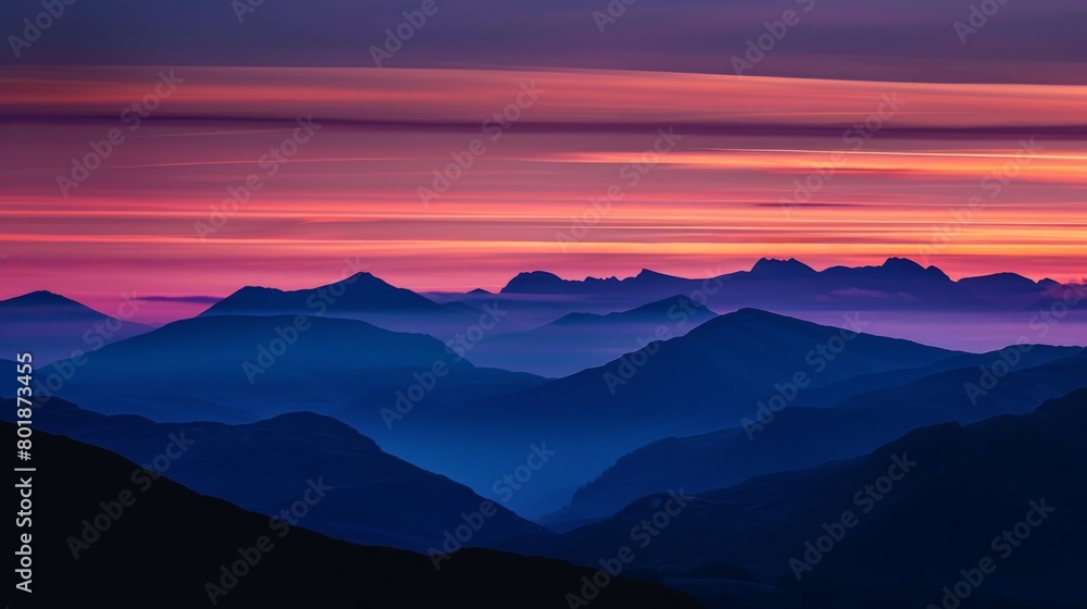 A majestic mountain range silhouetted against a darkening sky, with streaks of orange and purple painting the horizon.