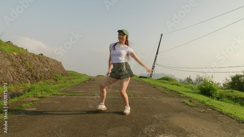 camera walking toward young female asiatic dancer dancing outdoor while wearing fancy cloth  photo