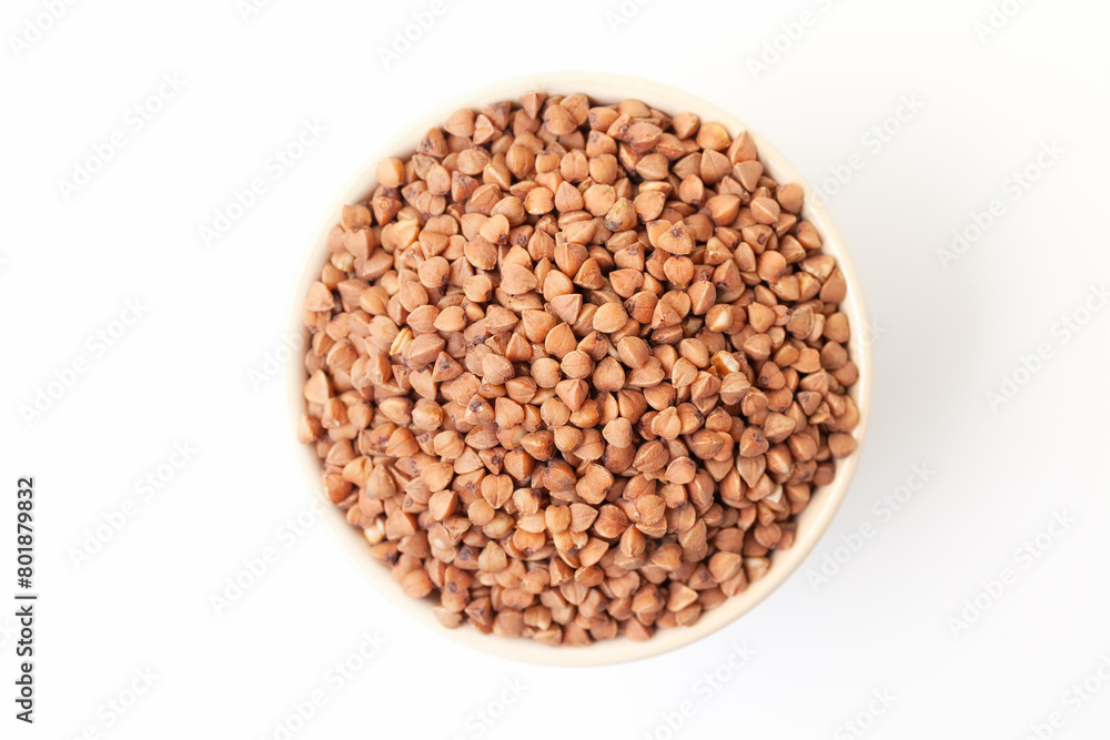Uncooked, brown buckwheat grains in bowl on white background. Dry buckwheat grains. Top view Uncooked, brown buckwheat grains in bowl on white background. Dry buckwheat grains. Top view
