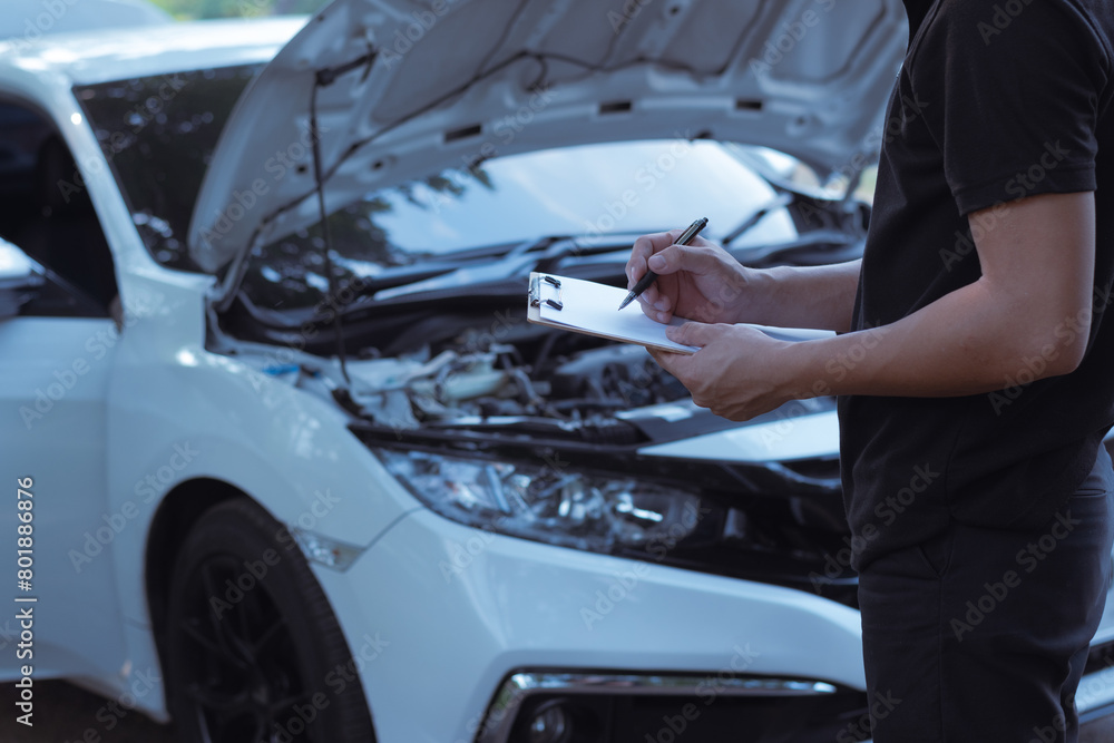 Automobile repairman writing job checklist on clipboard Automobile repairman writing job checklist on clipboard