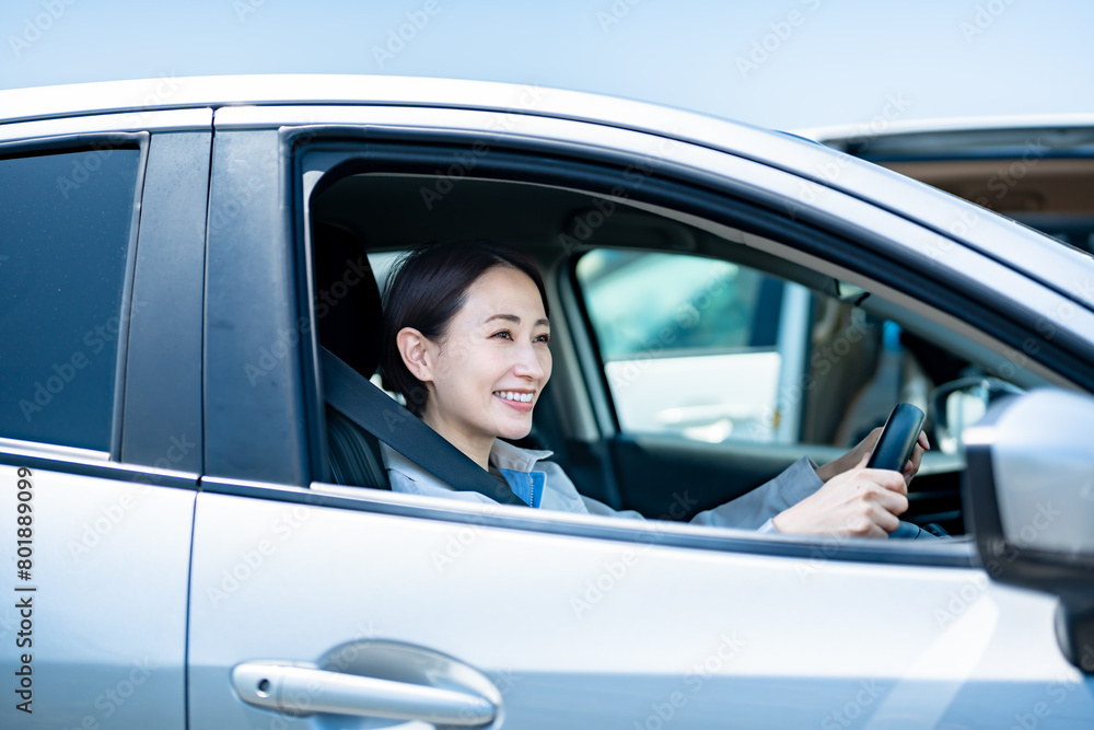 車に乗った作業着を着た笑顔の日本人女性 車に乗った作業着を着た笑顔の日本人女性