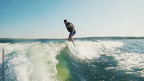 A man rides a wakeboard after a boat. Fun on the water during the hot summer on the lake.