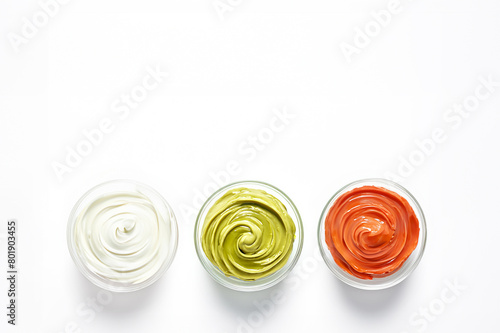 Three bowls with white, green, and red gourmet sauces, with whirls on white background. Сream of pistachios, almonds and peanuts with tomato. Healthy eating, veganism or natural food. Copy space