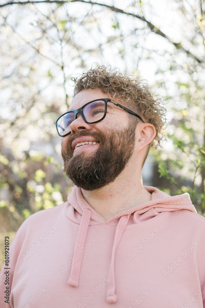 Man with beard and mustache on smiling face near sakura flowers or blooming spring tree. Soft and gentle concept. Bearded man with stylish haircut with flowers on background, close up. Hipster near Man with beard and mustache on smiling face near sakura flowers or blooming spring tree. Soft and gentle concept. Bearded man with stylish haircut with flowers on background, close up. Hipster near