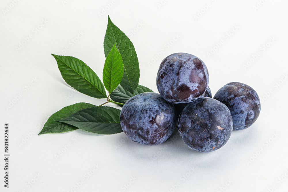 Raw purple plums heap with leaves Raw purple plums heap with leaves
