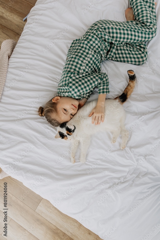a cute 6-year-old girl fell asleep sweetly next to a fluffy cat on her bed. Child with cat sleep on the white bed a cute 6-year-old girl fell asleep sweetly next to a fluffy cat on her bed. Child with cat sleep on the white bed