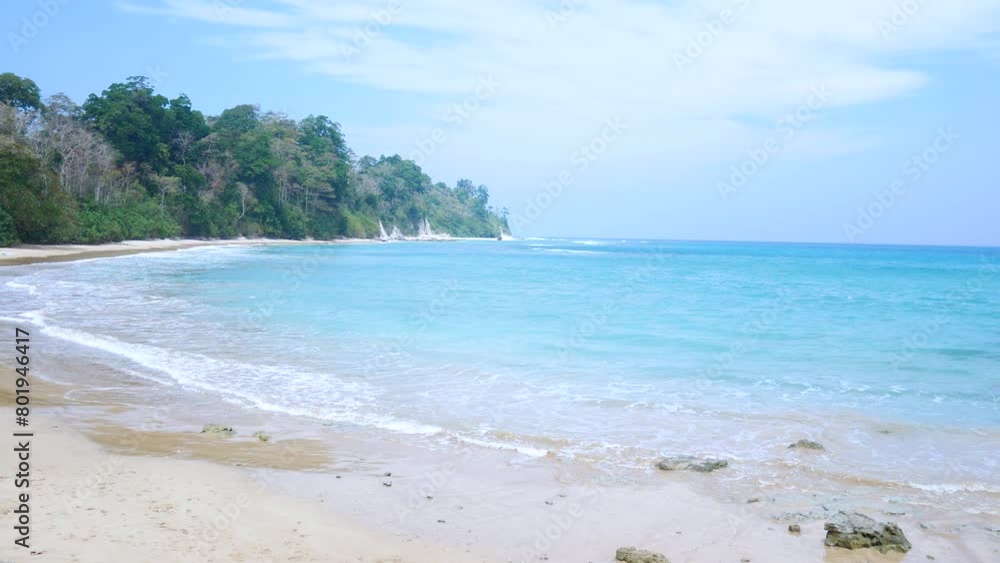 Crystal clear water lapping on tropical beach in the andaman islands. Turquoise water lapping gently on a pristine sandy beach with green jungle in the background Crystal clear water lapping on tropical beach in the andaman islands. Turquoise water lapping gently on a pristine sandy beach with green jungle in the background