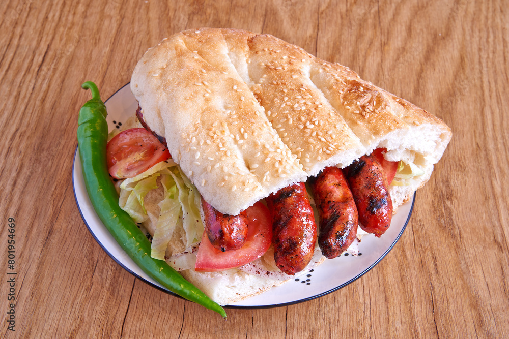Merguez kebab sandwich on decorated plate on wooden textured table