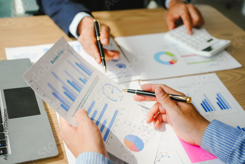 Desk-bound businessman calculates figures, verified accounts, and collaborates in discussions. Proficient in using calculators, aiding each other, and managing annual tax accounts in the audit office photo