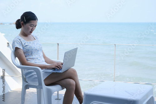 Young asia woman playing laptop computer on tropical beach