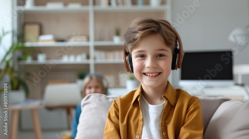 Cheerful young boy with headphones, engaging with technology in a modern living room