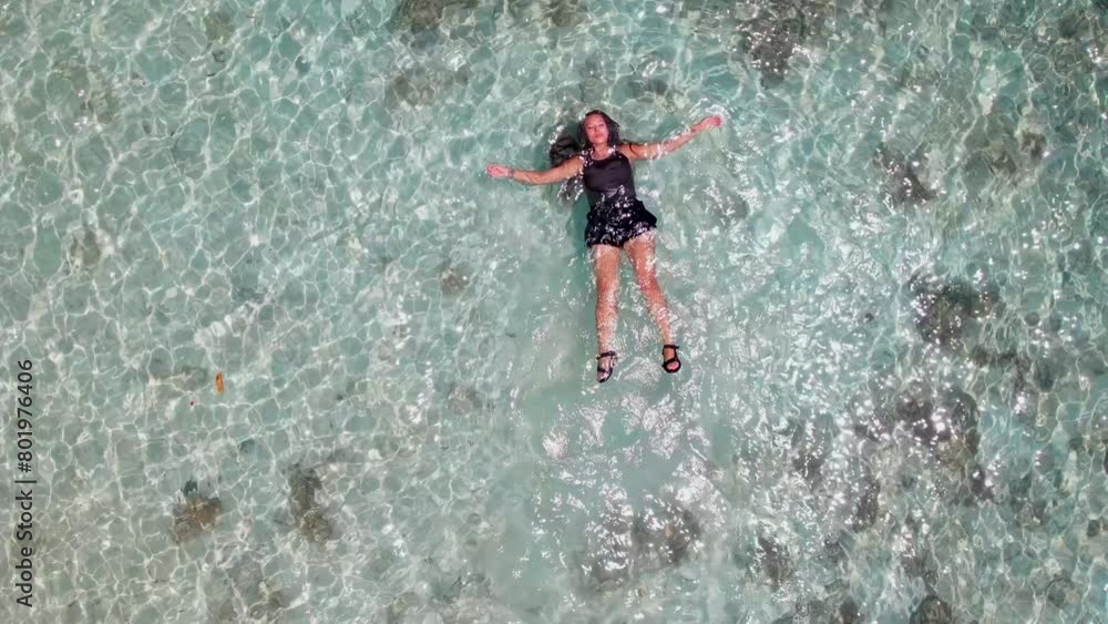 High above, an aerial view captures a swimmer floating with outstretched arms in crystalline waters, an embodiment of freedom and peace. Captured serenity, in slow motion. High quality 4k footage High above, an aerial view captures a swimmer floating with outstretched arms in crystalline waters, an embodiment of freedom and peace. Captured serenity, in slow motion. High quality 4k footage