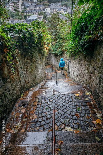 Photos Small alley where a woman in a blue raincoat descends the stairs from the historic Viaduct in the town of Morlaix, France