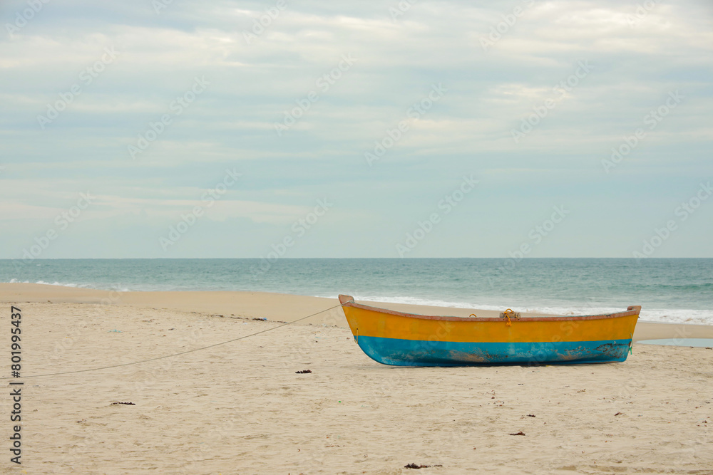 Traditional Wooden fishing boat in blue and yellow colors on white sand beach in Ghost Town near to Dhanushkodi beach Traditional Wooden fishing boat in blue and yellow colors on white sand beach in Ghost Town near to Dhanushkodi beach