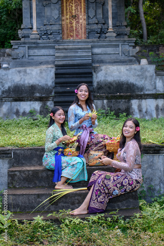 Group of Balinese women dressed in colorful traditional garments, carrying flower offerings 