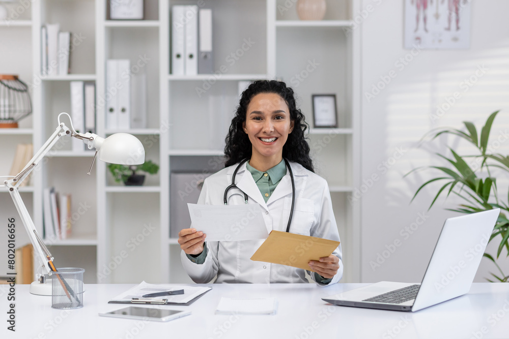 A pleasant and professional female doctor in a well-lit office, holding documents and smiling at the camera, conveying trust and care. A pleasant and professional female doctor in a well-lit office, holding documents and smiling at the camera, conveying trust and care.