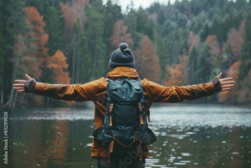 A Solo traveler backpacker opening his arms arriving at the lake in the forest, embracing the nature, enjoying the travel, travelers life photo