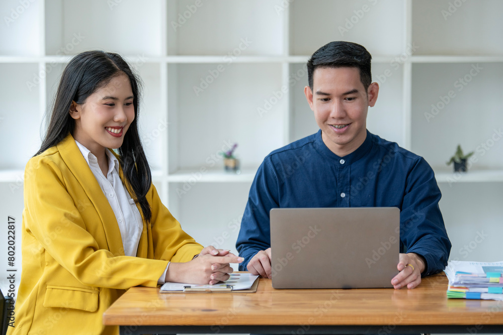 Professional Asian male and female colleagues discuss work on a laptop in a bright modern office, looking engaged and focused. Professional Asian male and female colleagues discuss work on a laptop in a bright modern office, looking engaged and focused.