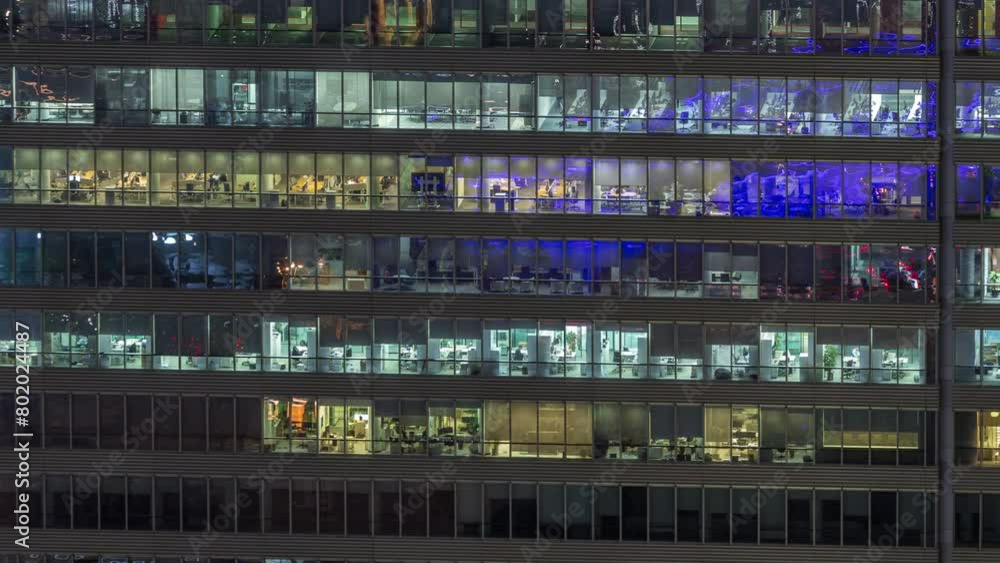 Frontal view of night facade of business tower building with a lot of windows with light timelapse. Life in every window. Aerial view of the glass facade of an office skyscraper. Frontal view of night facade of business tower building with a lot of windows with light timelapse. Life in every window. Aerial view of the glass facade of an office skyscraper.