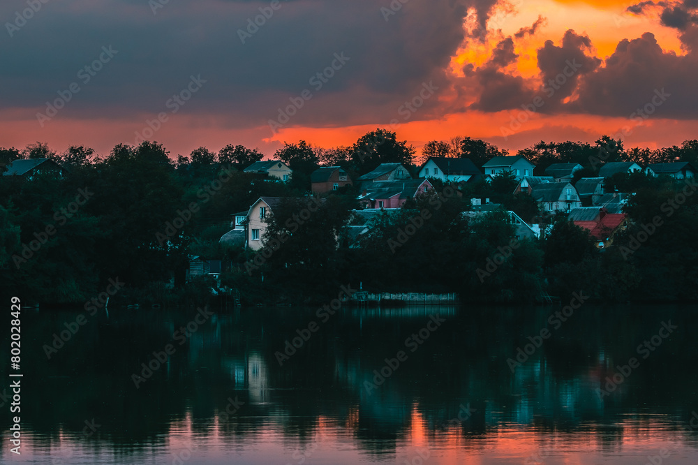 Obraz premium Sunset over the village near the lake